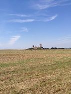 distan aged castle behind plowed field