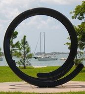 abstract ring sculpture in view of sailboats on water
