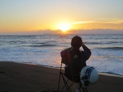 girl is sitting on a chair on the beach