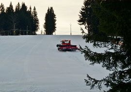 groomer on ski slope in winter landscape