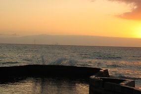 Beautiful waterscape with colorful sunset on the horizon behind the hills