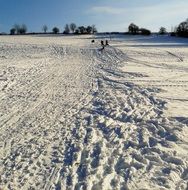 tracks on snow and distant people in winter landscape
