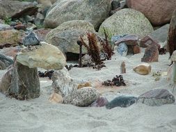 stones and boulders on white sand on the coast