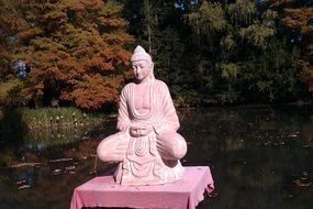 pink statue on the lake among the autumn forest