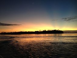 sunset behind forest at water