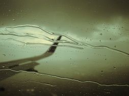 monochrome photo of airplane is reflected in the wet glass