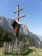 fenced wooden cross in mountain landscape