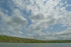 white clouds in the sky above the river
