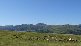 green field with stones near the mountains in Georgia