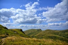 green hills under the blue sky with clouds