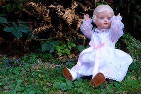 doll in a white dress in a green forest