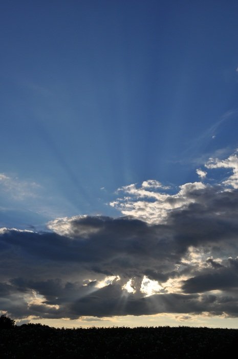 the sun's rays shine from behind the white clouds