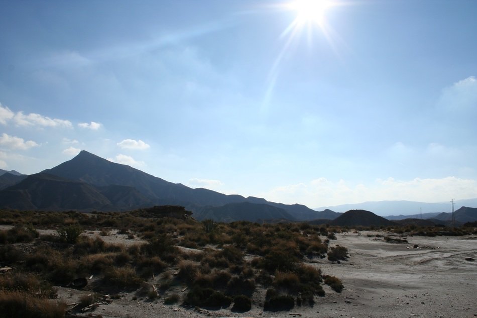 A picturesque desert against the background of volcanic rocks in the glare of the sun