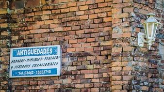 sign with inscriptions and blue stripes on a brick wall