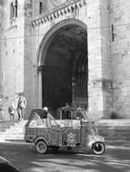 black and white photo of tricycle parked in front of the archway