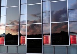 mirroring of evening sky with clouds on glass facade, germany, kassel