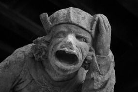 black and white photo of a gargoyle statue at dark background