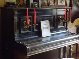 book with red candles stands on the piano