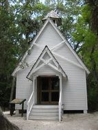 small white wooden chapel in the forest among green forest