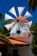 traditional windmill with white fabric wings at blue sky, greece
