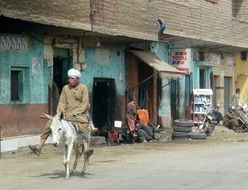 man on a donkey rides along the street