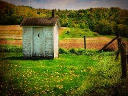 small wooden outhouse on a field in the countryside