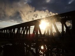 sunset through railing of bridge