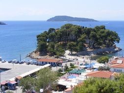 island with white buildings and green trees in greece