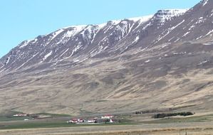 remote view of a farm at the foot of the mountains in iceland