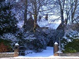 gateway to old building in garden at snowy winter