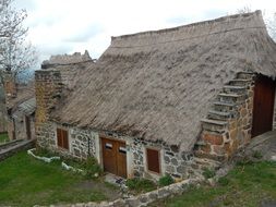 old stone house with a thatched roof on the farm