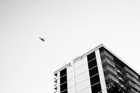 helicopter in sky at apartment building at cloudy sky background