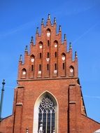 top of gothic red brick building at blue sky, Holy Trinity Church, poland, kraków