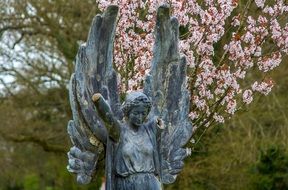 angel statue on a background of a blossoming tree