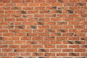 red brick wall with black patches of the construction