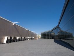 perspective of long glass facade opposite stone wall