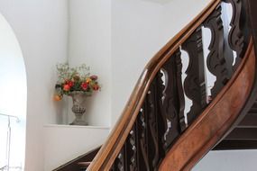 flowers in a vase near a wooden staircase