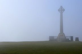 Stone monument in the shape of a cross in the fog