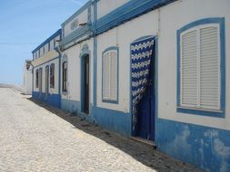 old building facade with shutters at windows and blue curtain at door, portugal