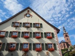 traditional building with flowers at windows in front of old church, germany, laufenburg
