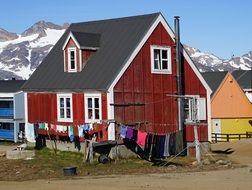 landscape of wooden house and clothes line in front of it and mountains