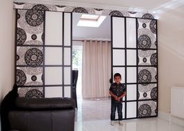 the boy is standing in front of the beautiful sliding doors in the living room