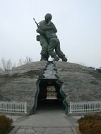military man hugs a Korean monument