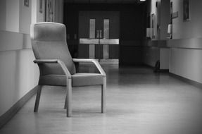 Black and white photo of the lonely chair in the hallway