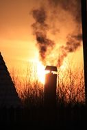 chimney against the background of the orange sun in the sunset