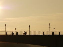 silhouettes of people on a bridge at sunset