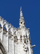 wall and the spire of the cathedral in Milan against the blue sky