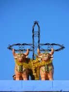 two sculptures of bulls and a cross on the temple in Arequipa