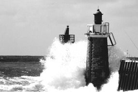black white photo of lighthouse and high ocean waves in France
