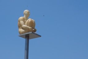 Statue of sitting man on a background of blue sky